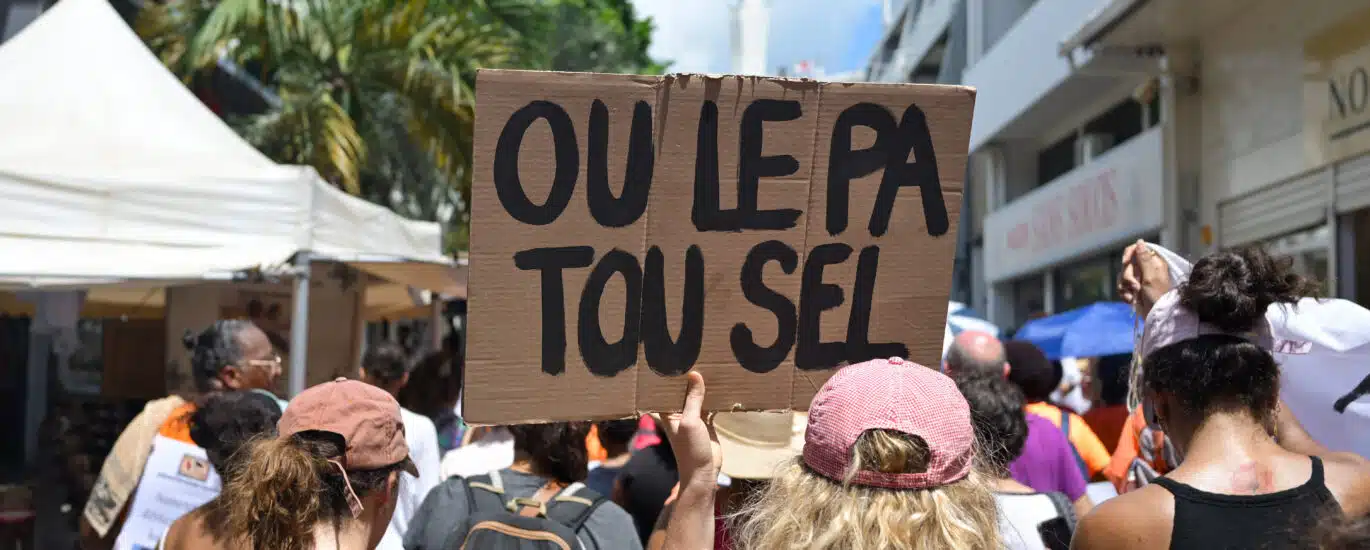 Une manifestante tient une pancarte sur laquelle on peut lire "Tu n'es pas toute seule" en créole.